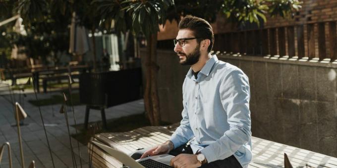 un, hombre, con, un, computador portatil, sentado, en, un, banco de parque