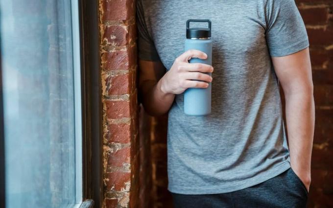 Deportista de cultivo con botella de agua.